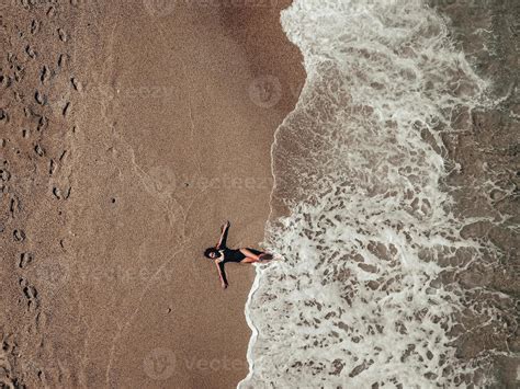 vue aérienne de dessus jeune femme allongée sur la plage de sable et