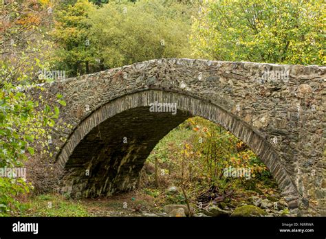 Snowdonia An Old Stone Bridge Partly Overgrown Small Arch Spanning A