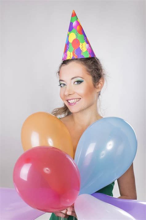 Brunette Woman In A Birthday Cap Holding Balloons And Smile Stock Photo