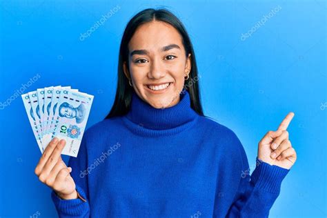 Joven mujer asiática sosteniendo billetes chinos de 10 yuanes sonriendo