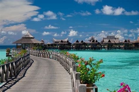 a wooden walkway leads to the beach and over water huts on stilts in ...