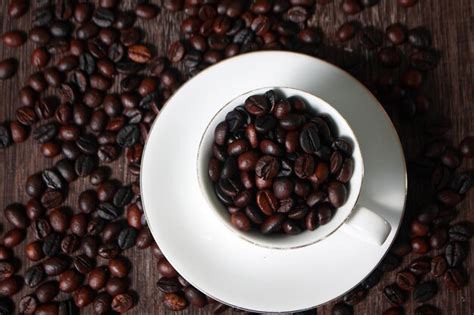 Premium Photo Dark Roasted Coffee Beans In White Cup With Blurred