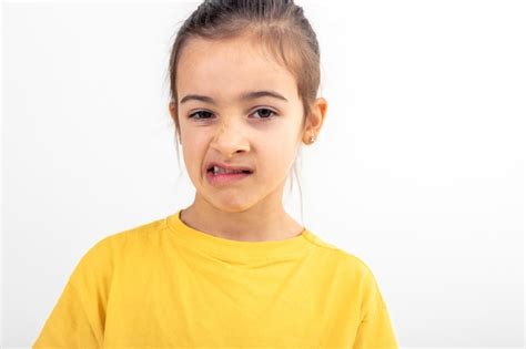 Una niña pequeña hace muecas de disgusto en un fondo blanco aislado