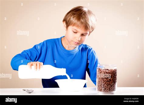 Kid Eating Breakfast Boy Pouring Milk Into A Bowl Of Cereal Stock