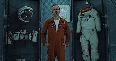 Aaron Paul as XX wears an orange jumpsuit with an American Flag patch ...