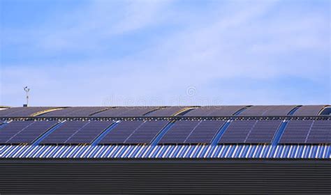 Many Solar Panels On Curved Steel Roof Of Industrial Building Against