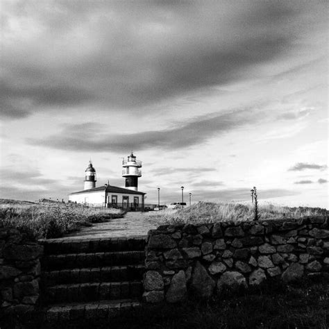 A Black And White Photo Of A Lighthouse On Top Of A Hill With Stairs