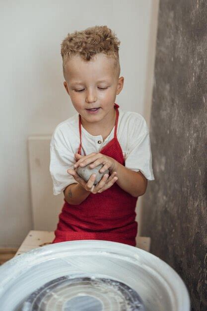 Un niño pequeño y lindo jugando con plastilina en un taller de cerámica