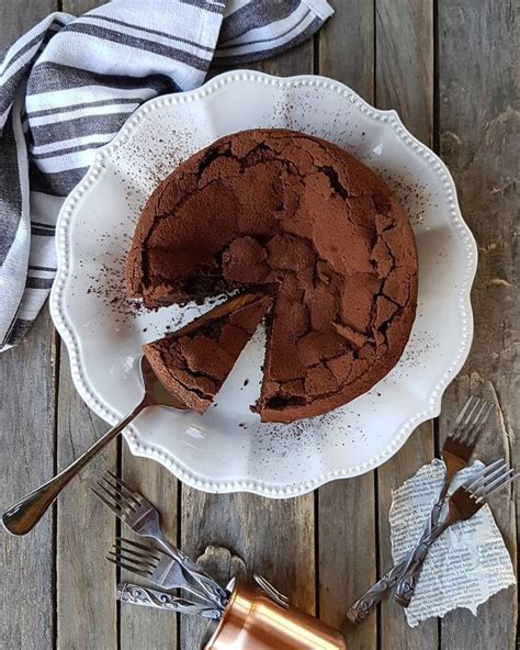 A Chocolate Cake On A White Plate With Two Forks