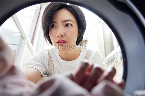 Young Woman At Home Doing Housework Using Washing Machine Picture And