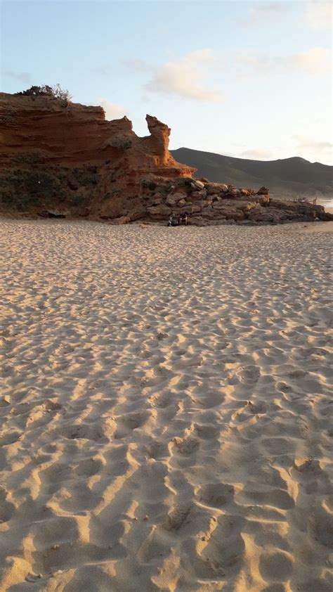 A Person Riding A Surfboard On Top Of A Sandy Beach