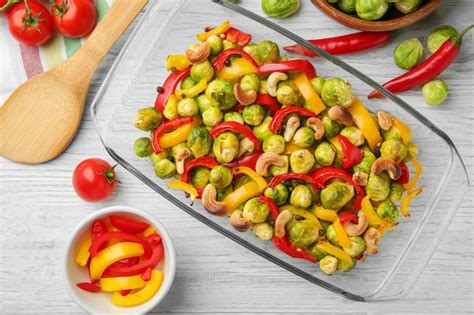 Premium Photo Glass Dish With Baked Brussels Sprouts Pepper And Nuts On Table