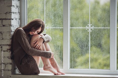 Beautiful Young Woman Sitting Alone Close To Window With Rain Drops