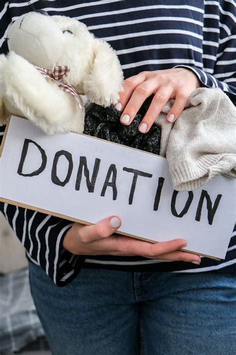 Female Volunteer Holding Donation Box With Old Used Toys And Clothes Indoors Happy Charity