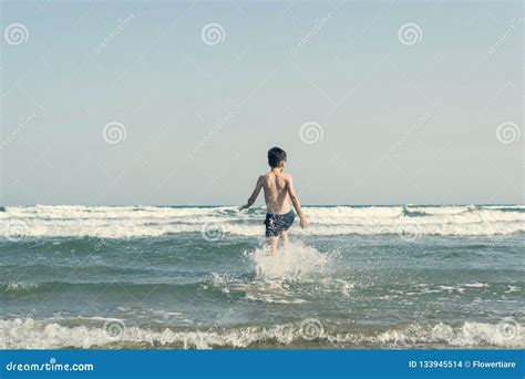 El Muchacho Que Salta En Ondas Del Mar Con Agua Salpica Concepto Foto