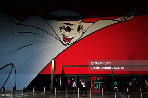 People walk past a large poster of Qatar 2022 mascot La'eeb in Doha ...