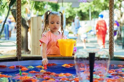 Una niña juega a la pesca infantil atrapa peces de juguete en la