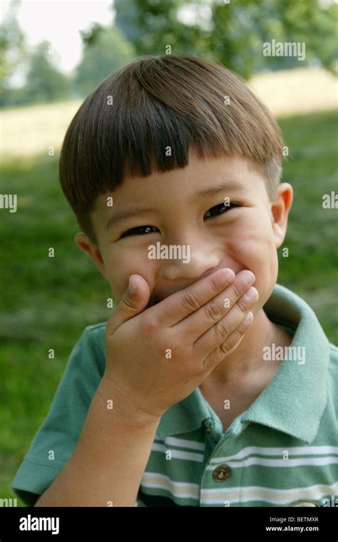 young boy outdoors laughing, holding his hand across his mouth Stock ...