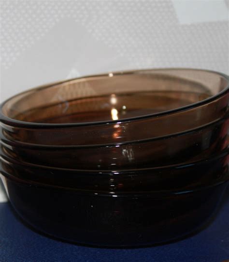 A Stack Of Brown Glass Bowls Sitting On Top Of A Blue Table Cloth Next To A White Wall