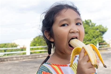 Premium Photo Portrait Of Cute Girl Eating Banana On Road