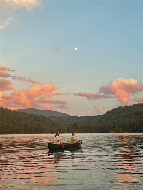 Two People In A Small Boat On A Lake With Mountains In The Background