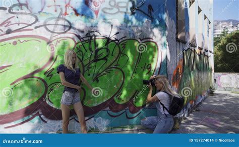 Girl Blonde Poses For A Girl To The Photographer On The Wall With