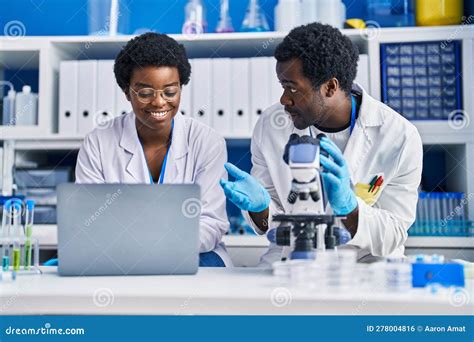 African American Man And Woman Scientists Using Laptop And Microscope