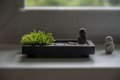 two small figurines sitting next to each other on a window sill with plants