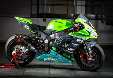 A Green And Black Motorcycle Is Parked In A Garage With Its Brake