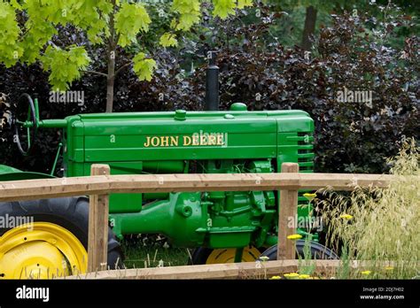 A Restored Vintage John Deere Tractor Behind A Wooden Fence Stock Photo