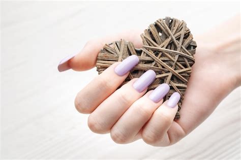 Manos de niña con delicada manicura morada y corazón decoratine Foto