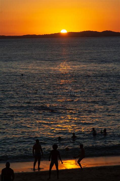 People Are Seen In Silhouette Having Fun On Porto Da Barra Beach