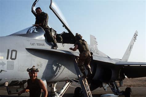 A Pilot Climbs Into The Cockpit Of An F A 18A Hornet Aircraft From