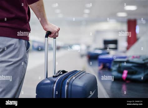 Traveling By Airplane Passenger Holding His Suitcase In Baggage Claim