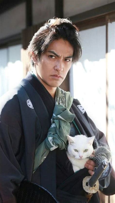 A Man Holding A White Cat In His Hand And Wearing A Kimono Over His