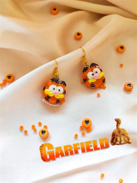 The Garfield Bear Earrings Are On Display Next To An Orange And Yellow