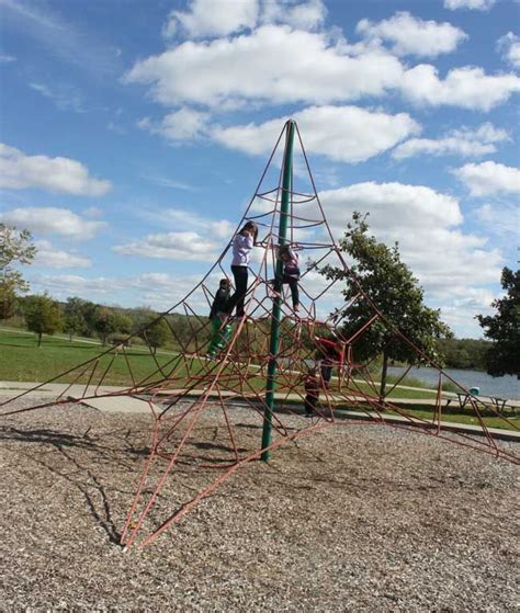 Two Children Are Playing On A Metal Playground Set With Ropes And