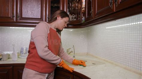 A Pregnant Woman Carefully Scrubs The Kitchen Sink With A Kitchen