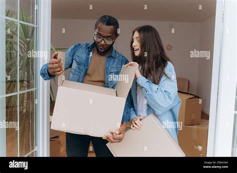 Happy Couple Opens A Cardboard Box With Things Unpacking The Box When