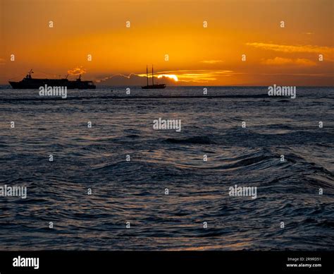 Sunset Over The Pacific Ocean As Seen From A Maui Beach Glows Bright Orange And Highlights Waves