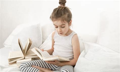 Cute Little Girl Reading a Book on the Bed in the Bedroom Stock Image ...