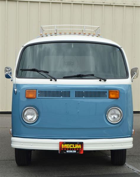 An Old Blue And White Van Parked In Front Of A Metal Building With Its