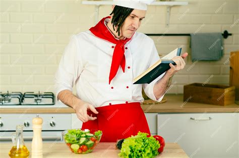 Premium Photo Young Man Dressed As Chef Reading Recipe Book In