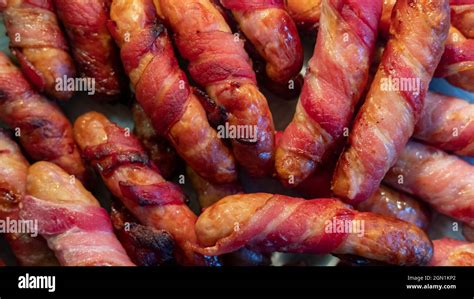 Sticky Bacon Wrapped Sausages Spread On A Plate To Cool Down Meat