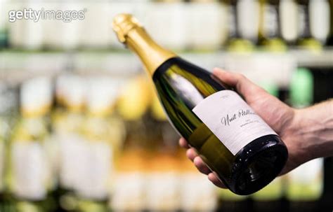 Sparkling Wine In Supermarket Or Alcohol Store Man Holding Bottle Of