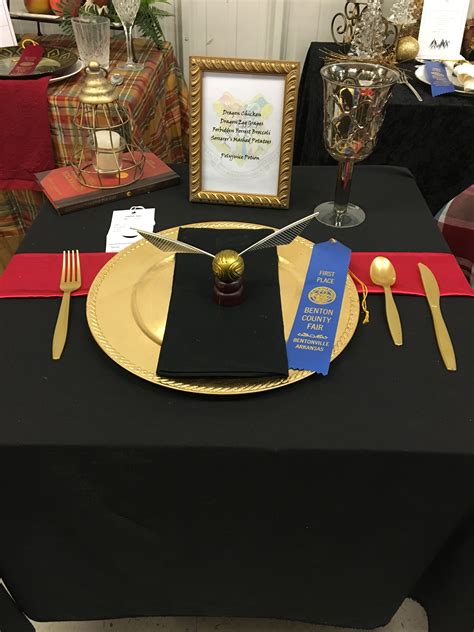 A Black Table With Gold Plates And Silverware