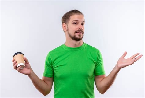 Hombre guapo joven en camiseta verde sosteniendo la taza de café