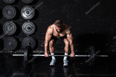 Joven hombre musculoso fuerte y sudoroso con grandes músculos que