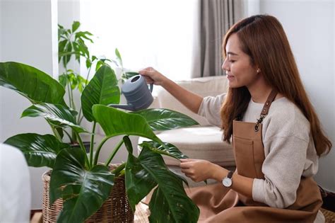 Uma Bela Jovem Asi Tica Cuidando E Regando As Plantas De Casa Regando A