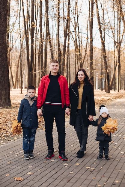 Familia caucásica va a dar un paseo por el parque de otoño con dos